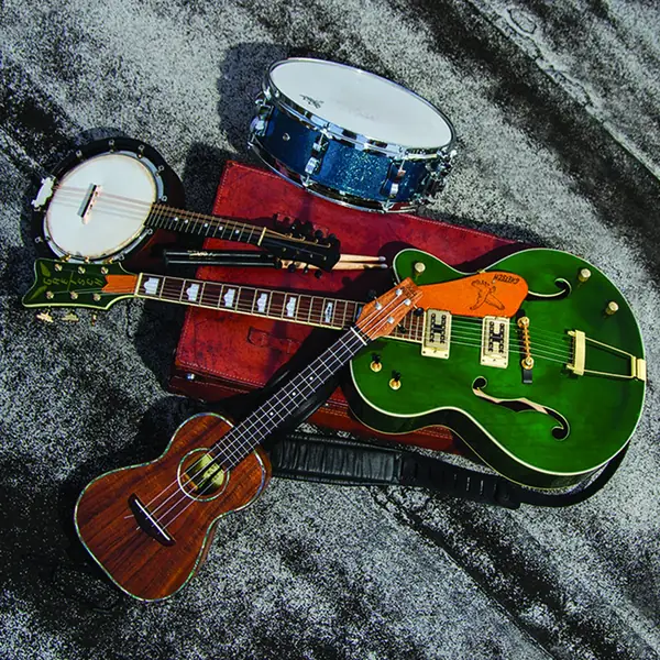 Electric and acoustic guitars, a banjo, a ukulele and a snare drum laid out together, ready to play